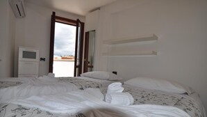 Hotellihuone, jossa on sänky, televisio ja avoimesta ovesta avautuva näkymä kaupunkiin.