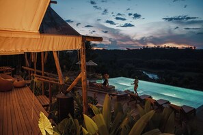 A wooden deck with lounge chairs and a pool, surrounded by tropical plants. - Glamping Entre Rios (Calarcá)
