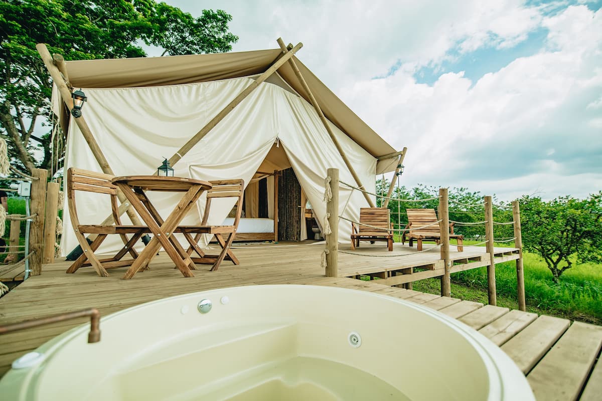 Alojamiento con carpa, jacuzzi, terraza de madera y zona de estar exterior.