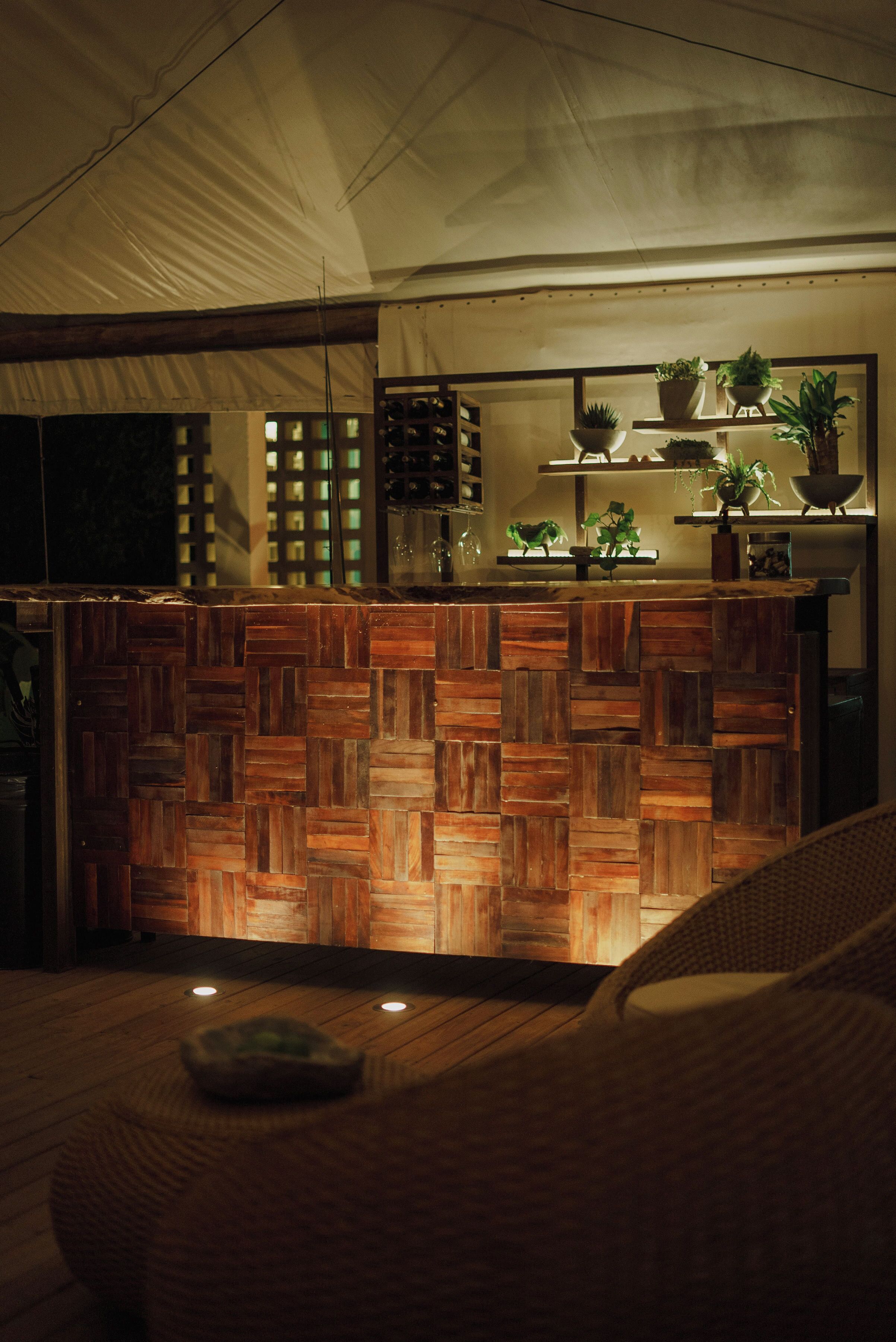 A wooden reception desk with potted plants, a mirror, and shelves with decorative items.