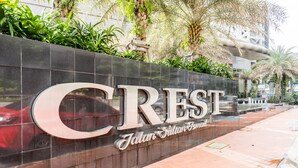 A sign for Crest International Hotel with a modern design and a view of the surrounding area.