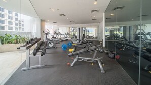 A modern gym with various exercise equipment, large windows, and a clean, spacious layout.