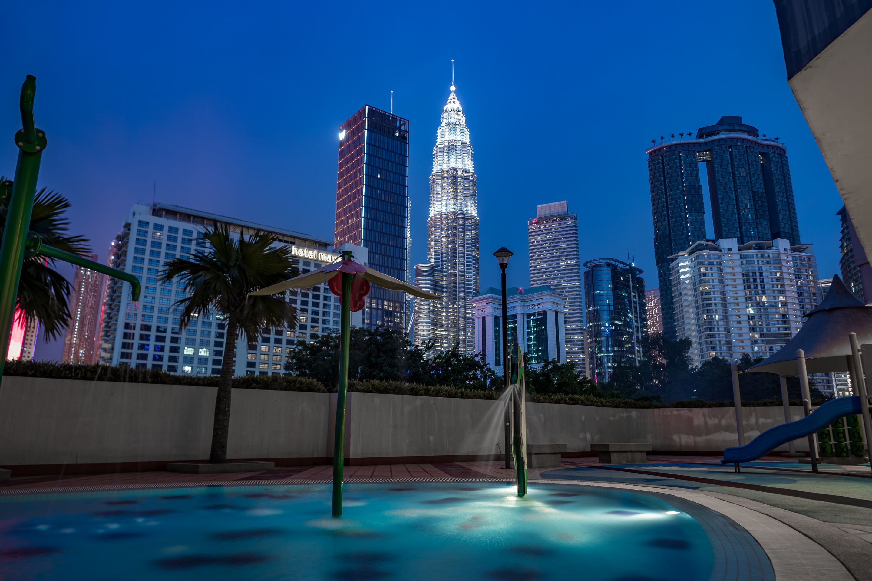 A cityscape with a prominent skyscraper, a swimming pool, and surrounding buildings.