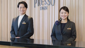Two individuals standing in front of a reception desk with a sign that reads 'Presso Inn'. - Keio Presso Inn Shinjuku (Tokyo)