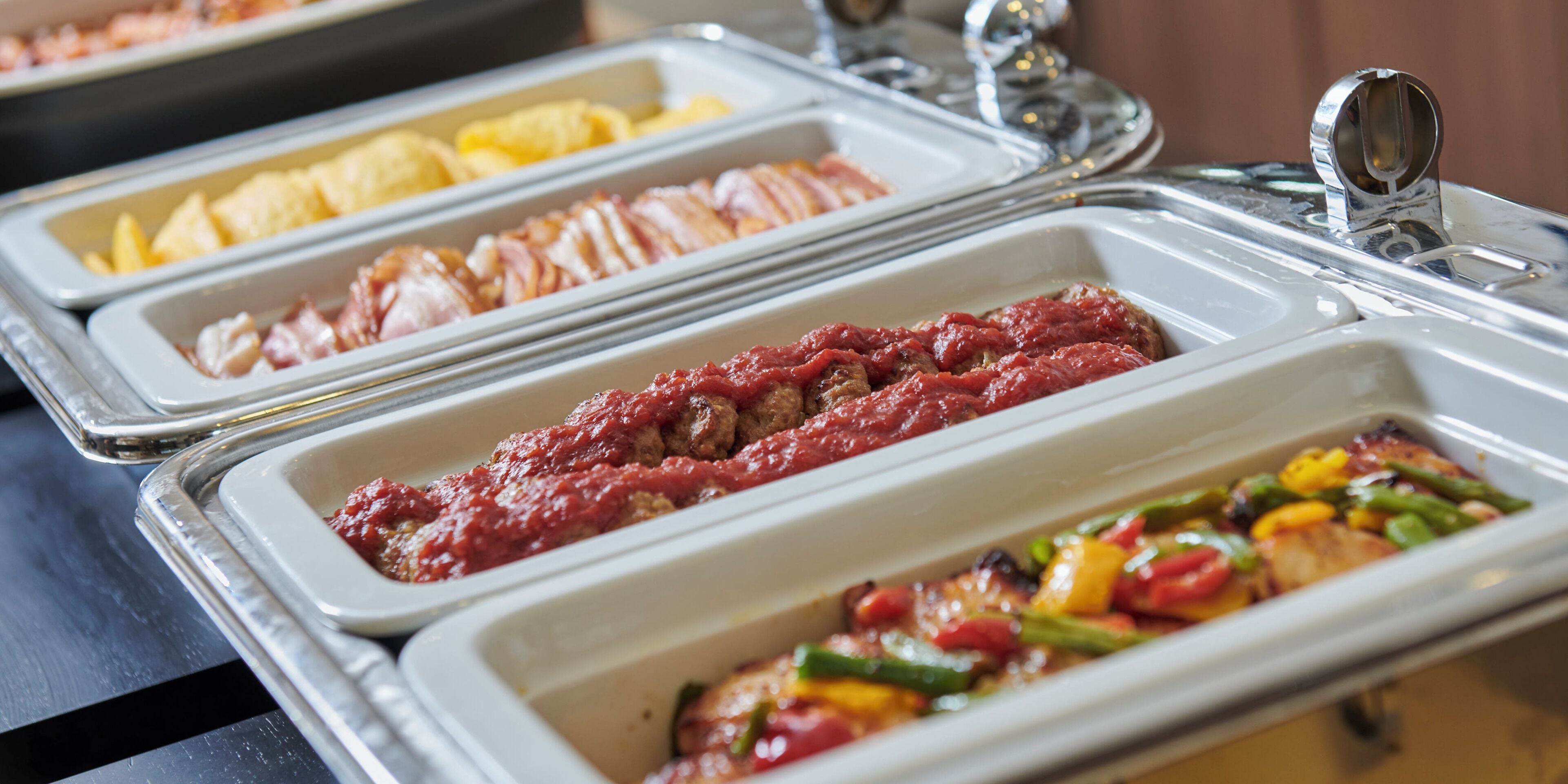 A buffet with various food options including meats, vegetables, and possibly some pasta dishes.
