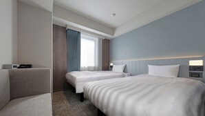 A hotel room with two beds, a sofa, a bedside table with a lamp, and a window with curtains. - Keio Presso Inn Shinjuku (Tokyo)