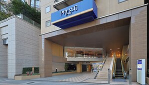A modern hotel entrance with a prominent signage, a staircase leading to the entrance, and a clear view of the interior.