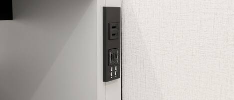 Eine weiße Wand mit einer schwarzen Steckdose und einem USB-C-Anschluss.