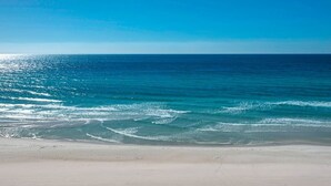 Una platja amb aigua blava i tranquil·la i un tram de sorra.
