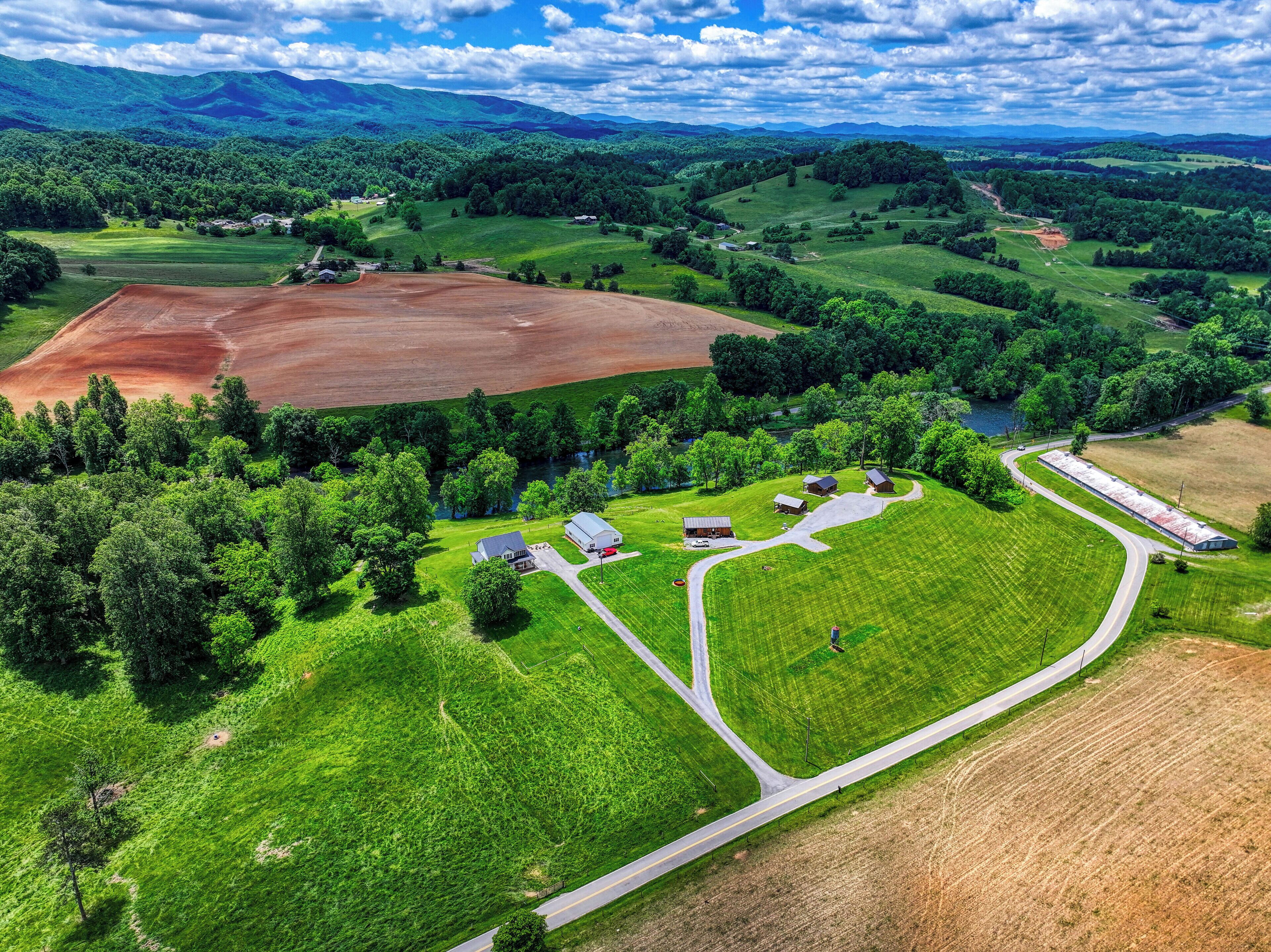A rural landscape with fields, a river, and scattered buildings.