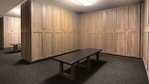 Una habitación con un banco de madera largo, varios armarios de madera y suelo alfombrado.