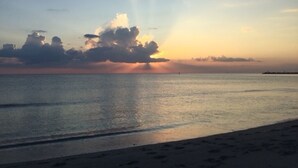 Een strand met een kalme zee en een zonsondergang.