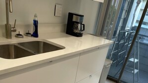 Een moderne keuken met een roestvrijstalen spoelbak, een koffiezetapparaat en een fles afwasmiddel.