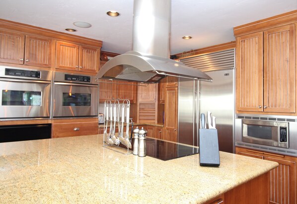 A kitchen with stainless steel appliances, wooden cabinets, and a granite countertop.