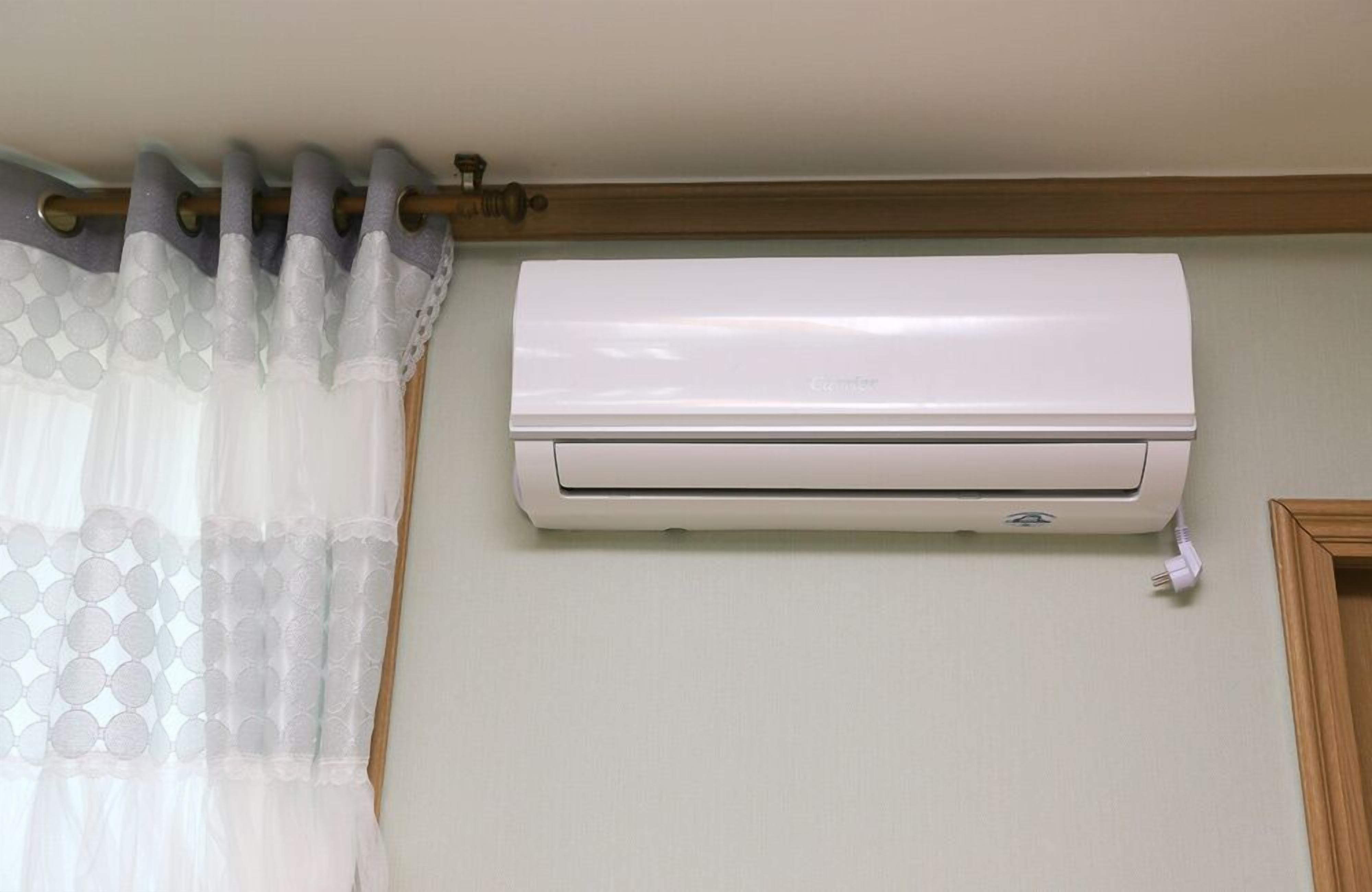 A white air conditioning unit mounted on a wall with a wooden trim above it.