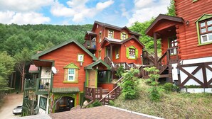Un ensemble de cabanes en bois rouge, rehaussées de touches de vert, se dressant sur fond de forêt.