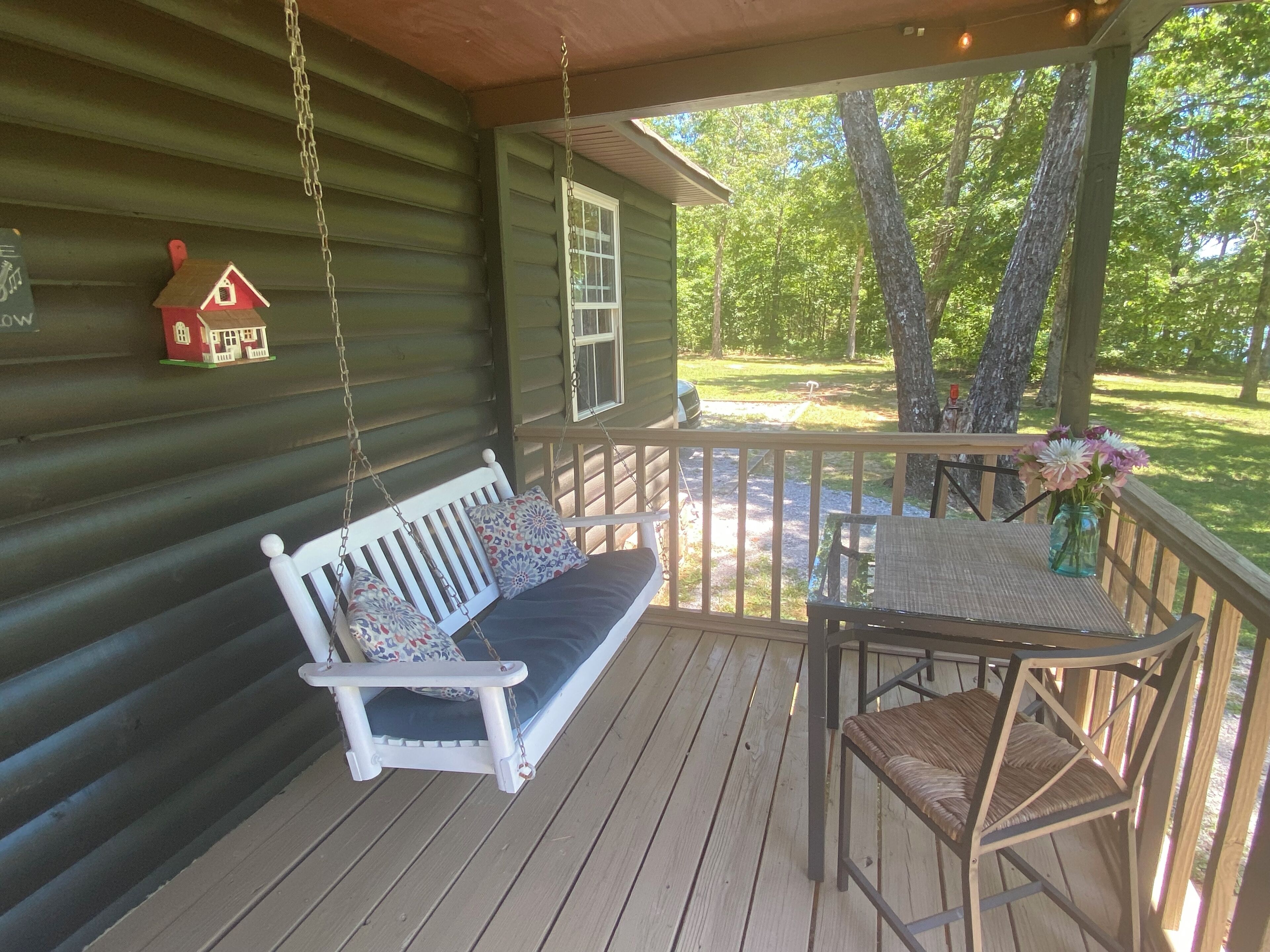 A wooden porch with a swing seat and a table with chairs.