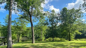Un parque con árboles, un área de picnic y un lago.