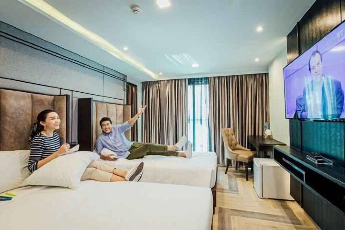 Ein Hotelzimmer mit zwei Betten, einem Fernseher, einem kleinen Tisch und einem Sessel.