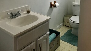 Une salle de bain équipée d’un lavabo, d’un miroir, de toilettes et de deux tableaux encadrés accrochés au mur.