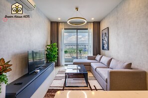A modern living room with a flat-screen TV, a sofa, a coffee table, and a balcony with a view.