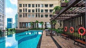 A swimming pool with a wooden deck, benches, and lifebuoys. - Dream House Apartment (Ho Chi Minh City)