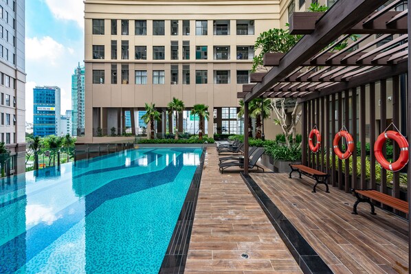 A swimming pool with a wooden deck, benches, and lifebuoys.