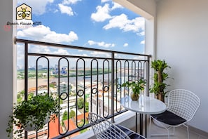 A balcony with a metal railing, a small round table, a white chair, and potted plants.