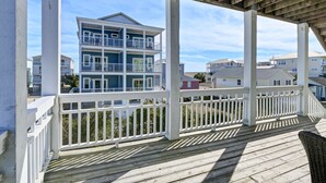 Um deck de madeira com guarda-corpos brancos, com vista para uma área residencial com edifícios altos.