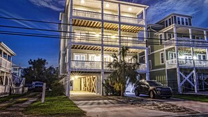 Um edifício residencial de vários andares, com varandas, garagem e entrada para carros.