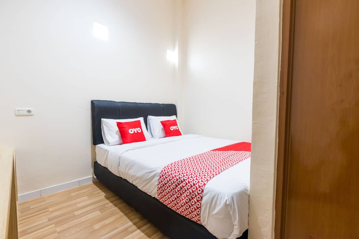 Ein Schlafzimmer mit einem Bett, weißen Wänden und Holzboden.
