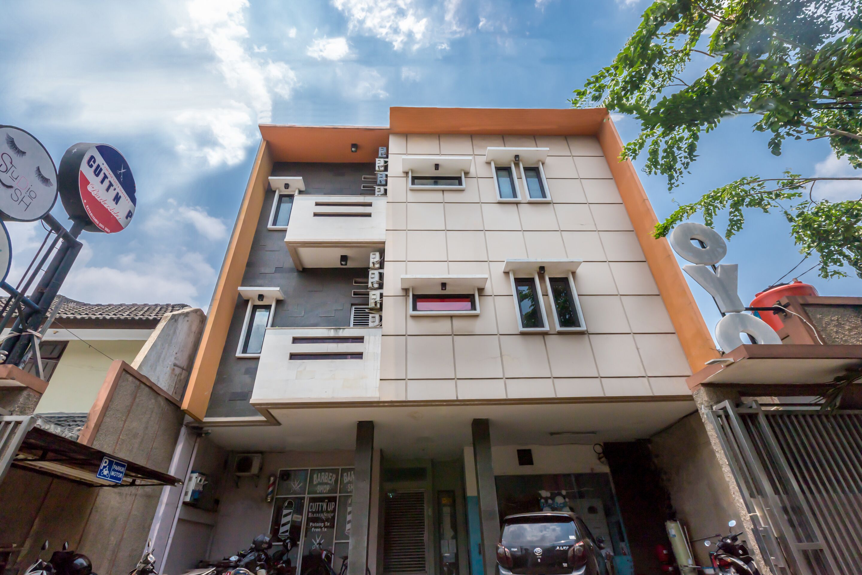 A modern multi-story building with a flat roof, several windows, and a visible garage entrance.