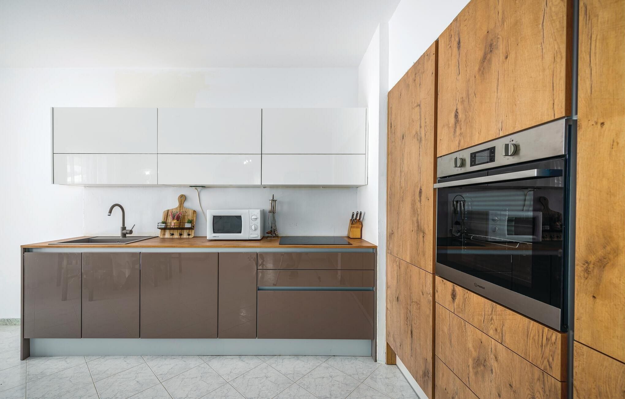 Une cuisine moderne avec des meubles de rangement en bois, un four encastré, un four à micro-ondes et un évier.