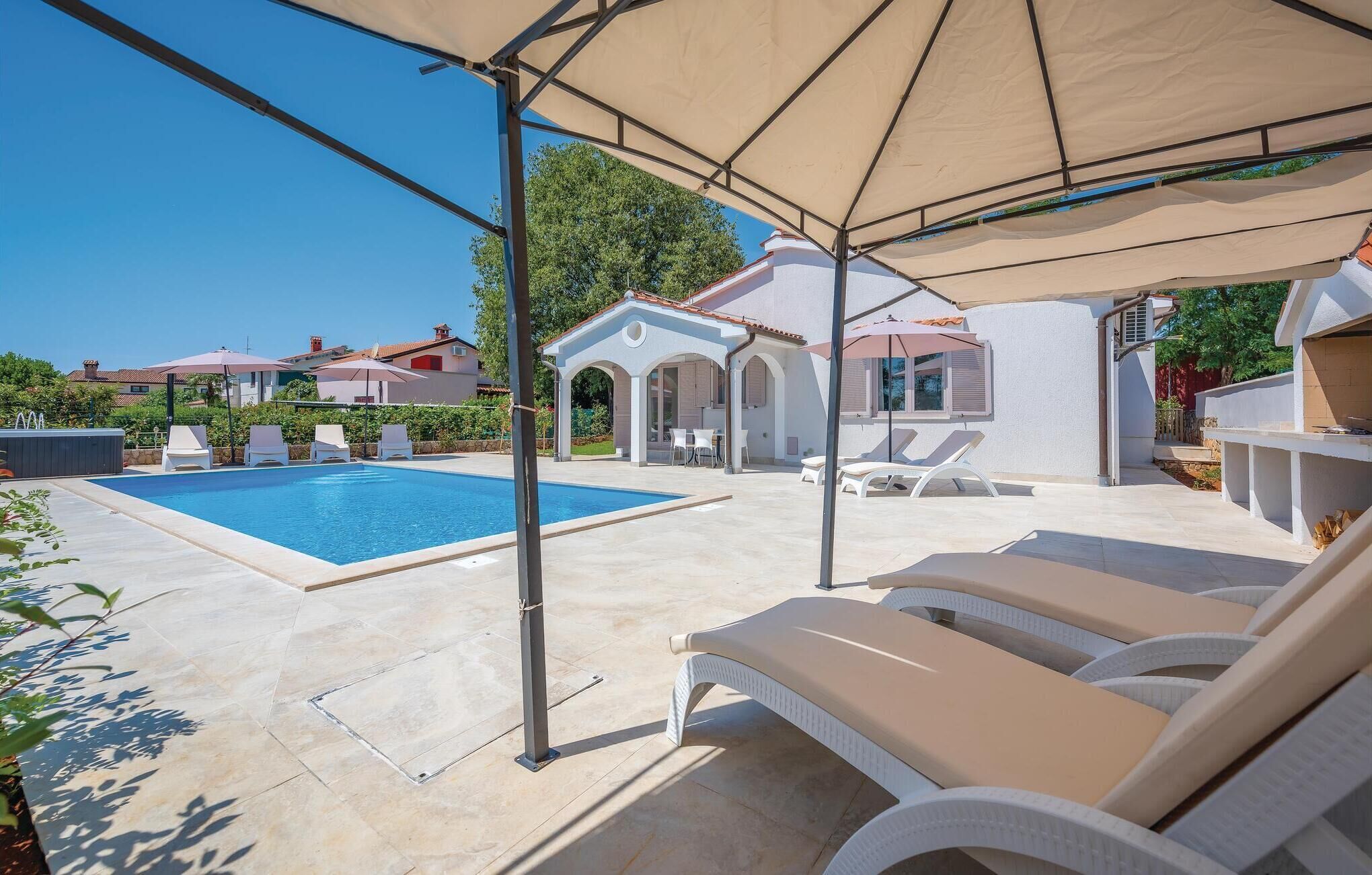 A pool area with lounge chairs and a covered seating area.