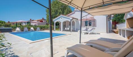 A pool area with lounge chairs and a covered seating area.