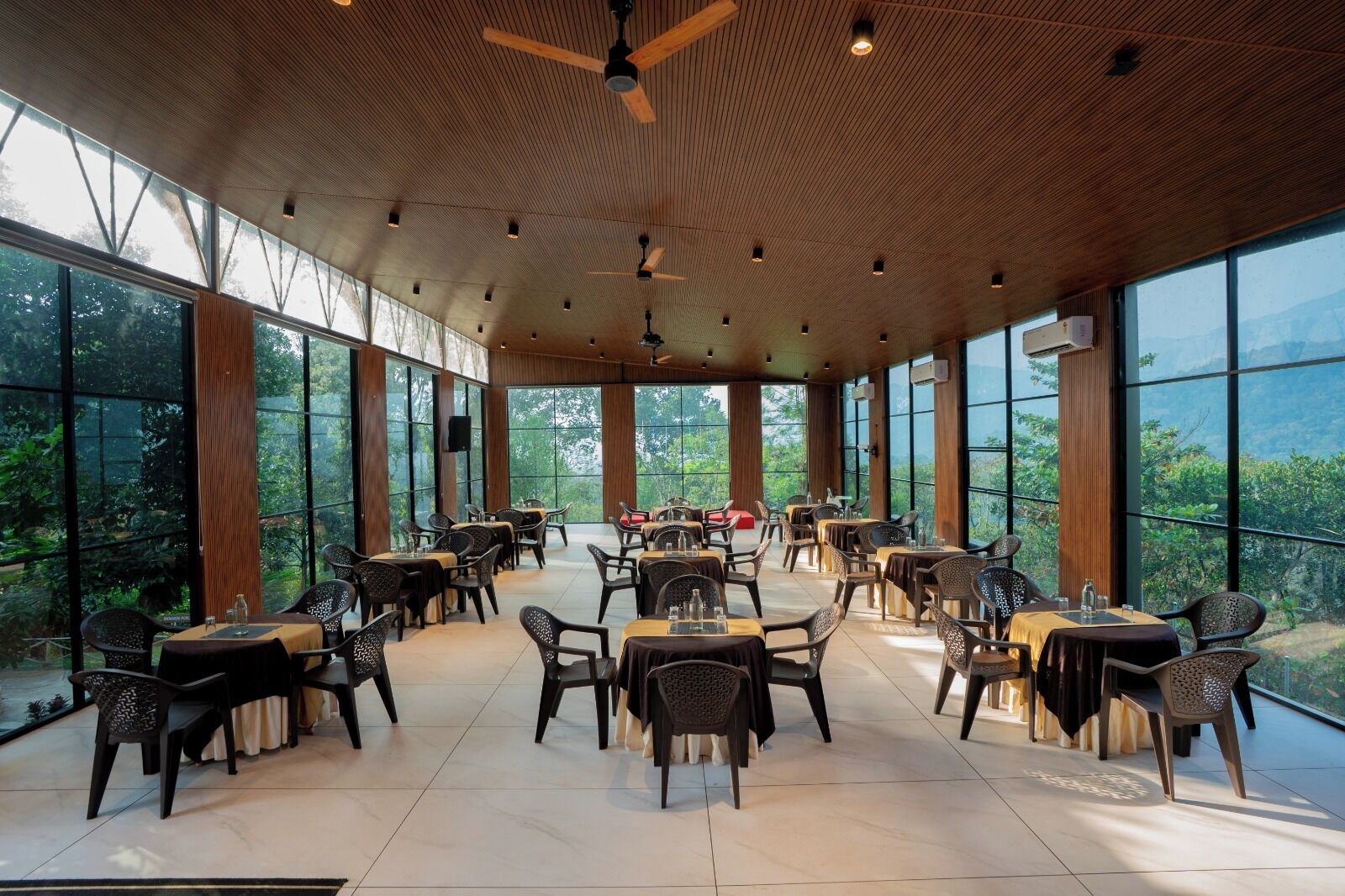 A spacious dining area with high ceilings, large windows, and a view of the outdoors.