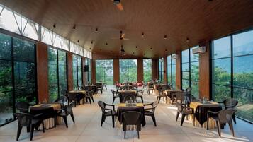 A spacious dining area with high ceilings, large windows, and a view of the outdoors.