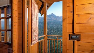 A wooden cabin with a balcony overlooking a mountainous landscape.