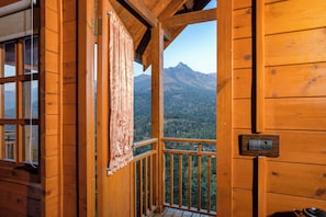 Una cabaña de madera con balcón que da a un paisaje montañoso.