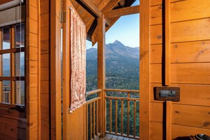 Una cabaña de madera con balcón que da a un paisaje montañoso.