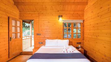A wooden room with a bed, a window, and a door leading outside.