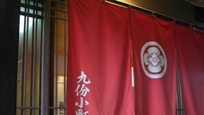 Een traditioneel Japans restaurant met rode vlaggen waarop de naam en het logo staan.