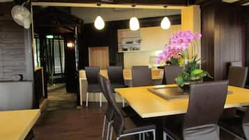A modern dining area with a wooden table, black chairs, and pendant lighting.