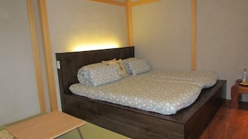 Un lit simple avec une tête de lit en bois, une table de chevet et une petite table placée devant le lit.
