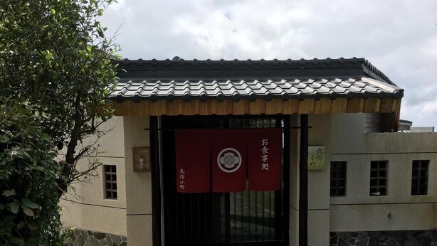 Een traditioneel Japans gebouw met pannendak en een pad van stenen dat naar de ingang leidt.