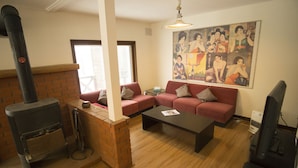 A living room with a brick fireplace, a sofa set, a coffee table, and a wall with a poster. - Annupuri Mountain View Lodge (Niseko)