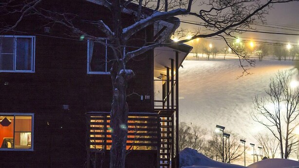 A wooden house with a balcony, a tree in front, and a snowy landscape. - Annupuri Mountain View Lodge (Niseko)