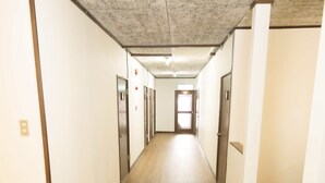 A long, narrow hallway with wooden flooring and white walls. - Annupuri Mountain View Lodge (Niseko)
