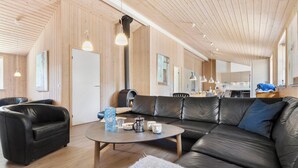Ein modernes Interieur mit einem Ledersofa, einem runden Tisch mit Getränken und einer sichtbaren Küchenzeile.