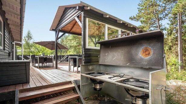 Ein Außenbereich mit Küche, Grill, Kochtöpfen und einer Holzterrasse.